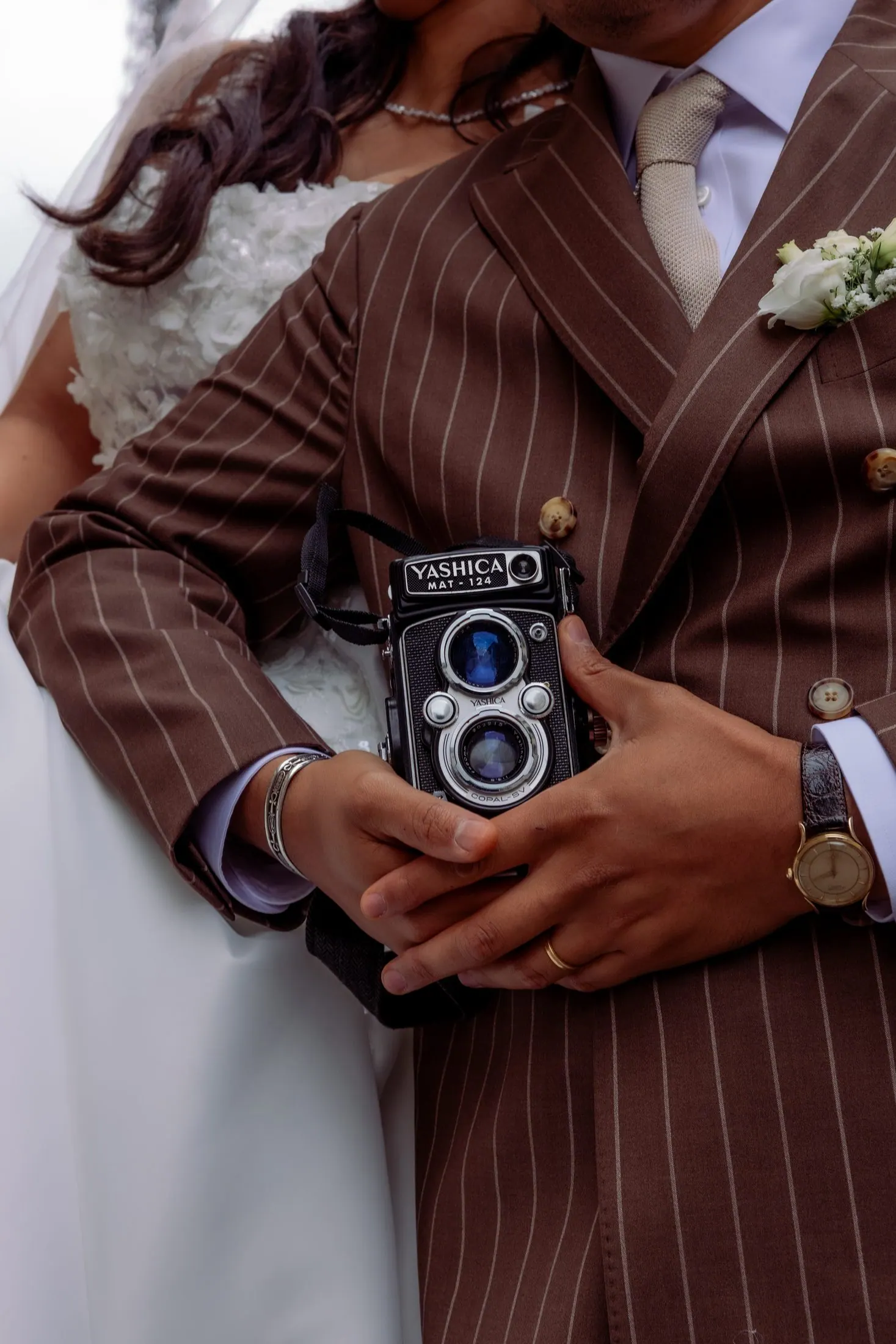 Mariés enlacés, le marié tenant un appareil photo argentique vintage